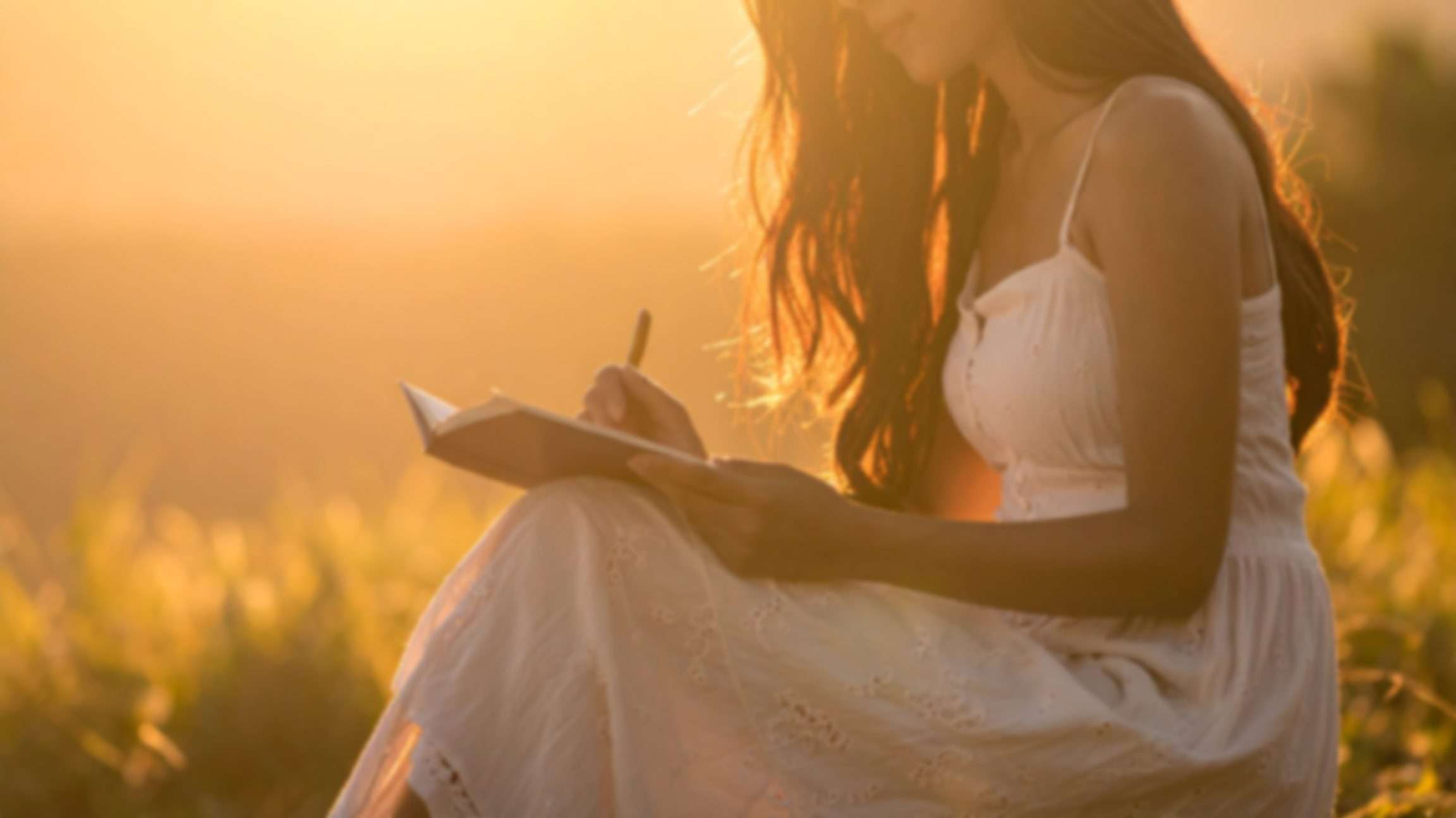 Soft golden light with a partial silhouette of woman journaling
